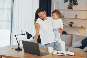 gebruik makend van laptop. moeder met haar weinig dochter is Bij huis samen foto