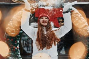 spelen met sneeuw. gelukkig jong vrouw staand buitenshuis en vieren Kerstmis vakantie foto