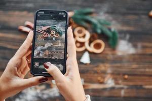 vrouw Holding telefoon. Kerstmis achtergrond met vakantie decoratie foto