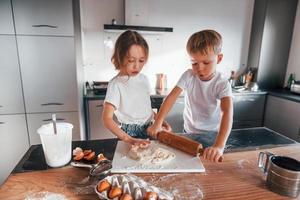 twee mensen samen. weinig jongen en meisje voorbereidingen treffen Kerstmis koekjes Aan de keuken foto