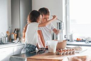 gieten water. weinig jongen en meisje voorbereidingen treffen Kerstmis koekjes Aan de keuken foto