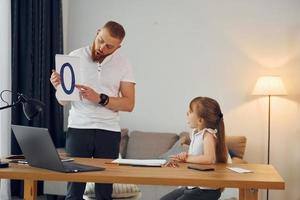 aan het leren brieven. vader met zijn weinig dochter is Bij huis samen foto