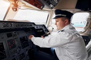 professioneel arbeider. piloot in formeel slijtage zit in de kuip en controles vliegtuig foto