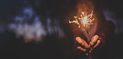 vrouw hand- genieten met brandend sterretje ontploffing in nieuw jaar partij foto