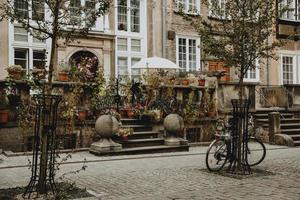 traditioneel terras in voorkant van de oud huis met veel van bloemen in historisch centrum van de Pools stad gdansk met fiets leunend tegen een boom foto