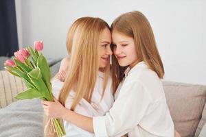 meisjes geeft bloemen. jong vrouw met haar dochter is Bij huis Bij dag foto