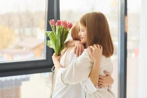 bloemen Bij vakantie. jong moeder met haar dochter is Bij huis Bij dag foto