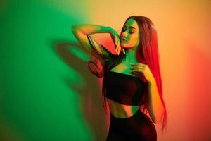 groen en rood kleuren. modieus jong vrouw staand in de studio met neon licht foto