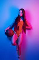 sexy lichaam. modieus jong vrouw staand in de studio met neon licht foto