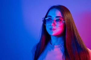 modieus jong vrouw staand in de studio met neon licht foto