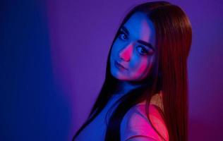 modieus jong vrouw staand in de studio met neon licht foto