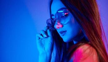 modieus jong vrouw staand in de studio met neon licht foto