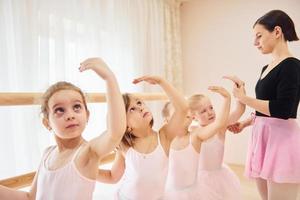 vrouw geeft les dans beweegt. weinig ballerina's voorbereidingen treffen voor prestatie foto