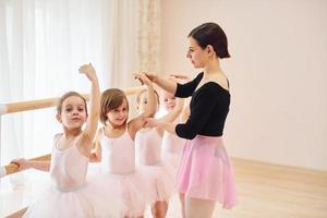 werken met coach. weinig ballerina's voorbereidingen treffen voor prestatie door beoefenen dans beweegt foto