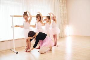 werken met coach. weinig ballerina's voorbereidingen treffen voor prestatie door beoefenen dans beweegt foto
