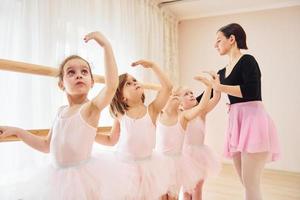 vrouw geeft les dans beweegt. weinig ballerina's voorbereidingen treffen voor prestatie foto