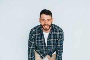 in in een plaid shirt. jong Mens in gewoontjes kleren staand binnenshuis in de studio foto