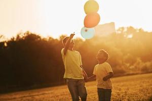 spelen met lucht ballonnen. twee Afrikaanse Amerikaans kinderen hebben pret in de veld- Bij zomer dag samen foto