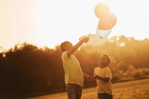 spelen met lucht ballonnen. twee Afrikaanse Amerikaans kinderen hebben pret in de veld- Bij zomer dag samen foto