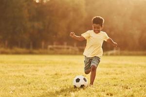 Toneelstukken voetbal. Afrikaanse Amerikaans kind hebben pret in de veld- Bij zomer dag foto