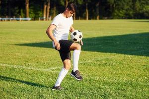 zonnig dag. jong voetbal speler hebben opleiding Aan de sportief veld- foto