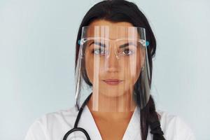 in beschermend gezicht masker. jong vrouw dokter in uniform is binnenshuis foto