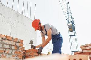 jong bouw arbeider in uniform is bezig Bij de onvoltooid gebouw foto