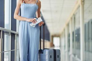 vrouw met ticket. jong reiziger is Aan de Ingang hal in de luchthaven foto