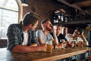 kant visie van vrienden met bier. mensen in gewoontjes kleren zittend in de kroeg foto