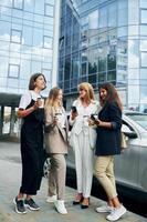 Dames in formeel slijtage is buitenshuis in de stad samen staand in de buurt zilver gekleurde auto foto