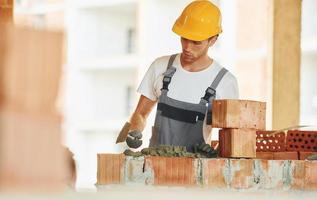 gebouw werkwijze. jong Mens werken in uniform Bij bouw Bij dag foto