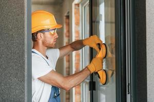 in beschermend dragen. jong Mens werken in uniform Bij bouw Bij dag foto