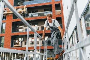 gebouw buitenkant. jong Mens werken in uniform Bij bouw Bij dag foto