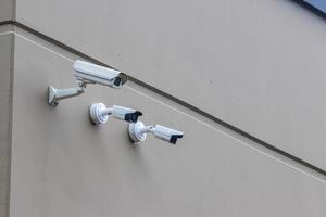 3 veiligheid camera's in een rij Aan een bruin gebouw muur foto