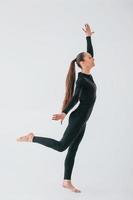 wit achtergrond. jong vrouw in sportief kleren aan het doen gymnastiek binnenshuis foto
