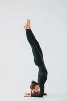 praktijk routine. jong vrouw in sportief kleren aan het doen gymnastiek binnenshuis foto