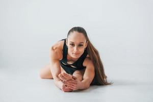 professioneel trainer. jong vrouw in sportief kleren aan het doen gymnastiek binnenshuis foto