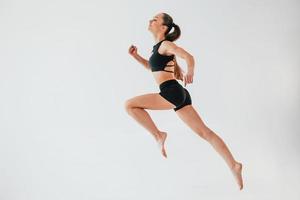 flexibiliteit van de lichaam. jong vrouw in sportief kleren aan het doen gymnastiek binnenshuis foto