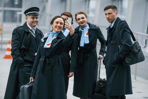 vliegtuig bemanning in werk uniform is samen buitenshuis in de luchthaven foto