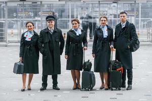 vliegtuig bemanning in werk uniform is samen buitenshuis in de luchthaven foto