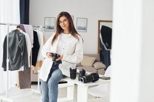 vrouw fotograaf in gewoontjes kleren is werken binnenshuis Bij dag foto
