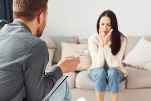 jong vrouw Bij een ontvangst Bij een psycholoog. zit Aan de sofa foto