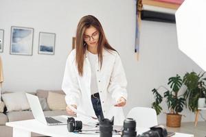 vrouw fotograaf in gewoontjes kleren is werken binnenshuis Bij dag foto