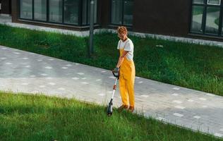 ver weg visie. Mens besnoeiing de gras met gazon verhuizer buitenshuis in de werf foto