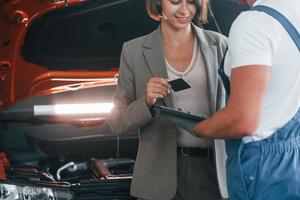 betalen voor onderhoud. Mens repareren vrouw auto- binnenshuis foto