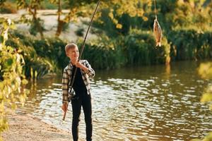 jongen in gewoontjes kleren in Aan vissen buitenshuis Bij zomertijd foto