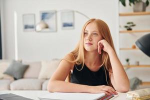 leunend Aan de tafel. vrouw tiener met blond haar- is Bij huis Bij dag foto