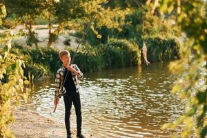 jongen in gewoontjes kleren in Aan vissen buitenshuis Bij zomertijd foto