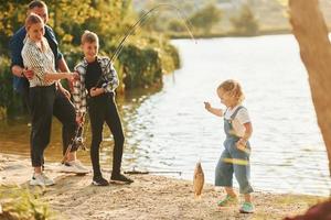 midden- formaat meer. vader en moeder met zoon en dochter Aan visvangst samen buitenshuis Bij zomertijd foto