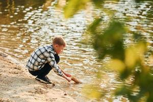 jongen in gewoontjes kleren in Aan vissen buitenshuis Bij zomertijd foto